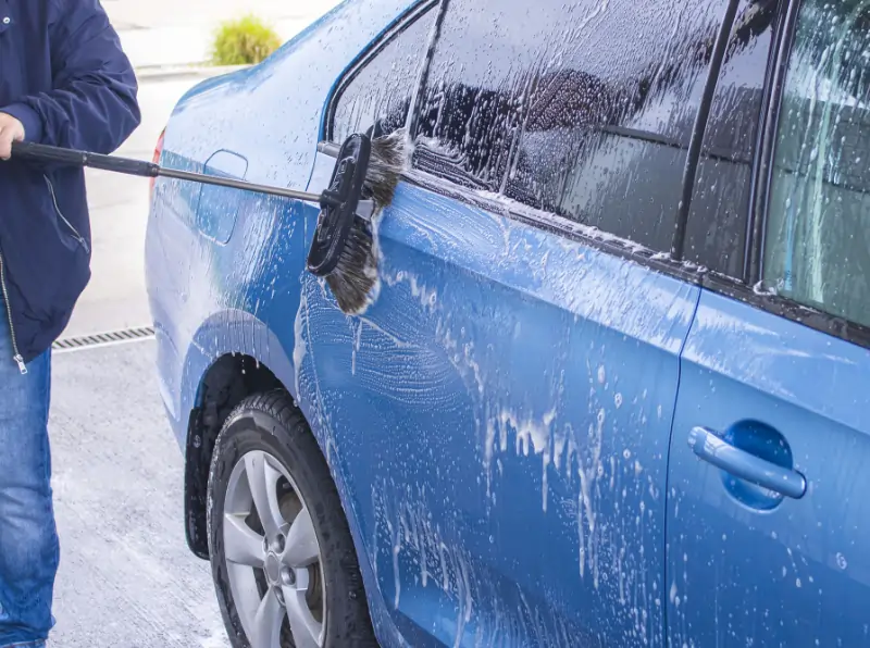 man washing car with foam brush