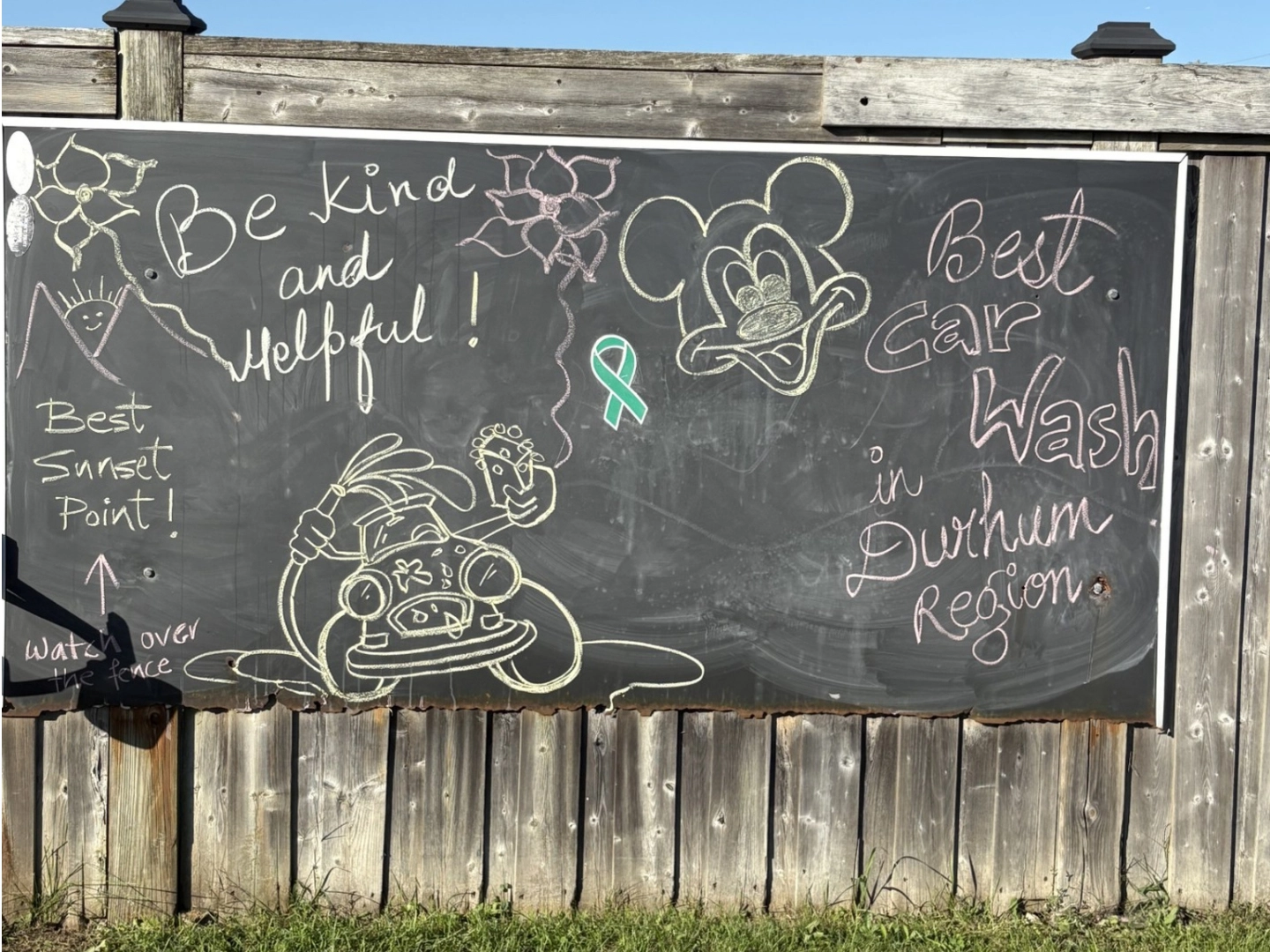 chalkboard doodling at brooklin car wash chalkboard with doodle art drawn on int hanging from a fence at Brooklin Coin Car Wash